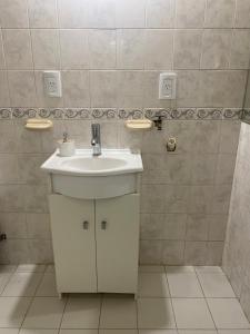a bathroom with a white sink and a tiled wall at Hogar in Río Gallegos