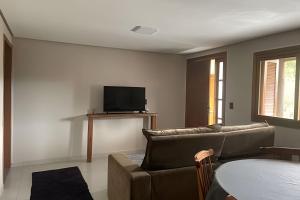 a living room with a couch and a tv at Casa das Bananeiras - 1 Quarto * Rota do Vinho in Bento Gonçalves