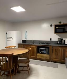 a kitchen with a wooden table and a refrigerator at Casa das Bananeiras - 1 Quarto * Rota do Vinho in Bento Gonçalves