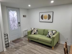 a living room with a green couch and a window at Private Entry-Modern & Bright Longueuil Suite in Longueuil