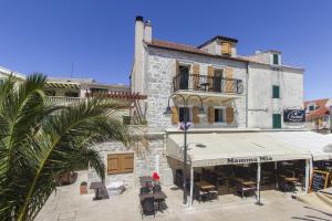 un bâtiment avec un restaurant et un palmier dans l'établissement Holiday Home Stonehouse Popožo, à Primošten