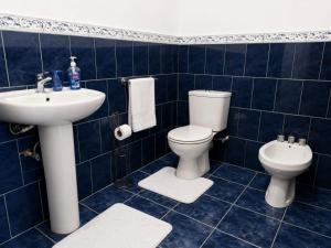 Ein blau gefliestes Badezimmer mit Toilette und Waschbecken in der Unterkunft Cozy Corner in San Fernando