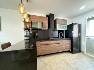 a kitchen with wooden cabinets and a black refrigerator at Casa Tulipanes Morelos, Alberca Climatizada, Jacuzzi y Roof in Morelos