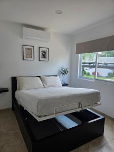 a bed in a white room with a window at Casa Tulipanes Morelos, Alberca Climatizada, Jacuzzi y Roof in Morelos +20 photos