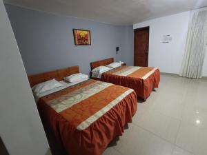 a hotel room with two beds with orange sheets at Hotel Pradera de los Celajes in Cajamarca