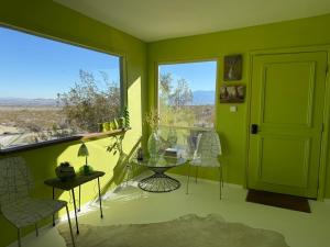 a green room with a table and chairs and a window at Casa Soza in White Water