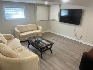 a living room with two chairs and a table and a tv at Newly Renovated 2BR Walkout Suite in the Heart of Kanata Ottawa in Ottawa