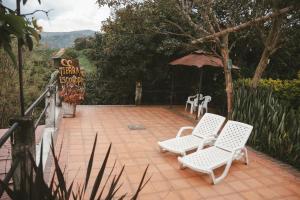 two white chairs and an umbrella on a patio at Tierra Mágica eje cafetero in Manizales