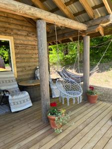 a porch of a cabin with a swing and a hammock at Miško sodyba in Gedvainiai