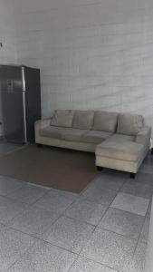 a couch sitting in a room with a refrigerator at Pousada Fortaleza SP 8 in São Paulo
