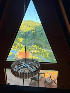 a room with a large window with a large chandelier at Chalés Aframe com café da manhã artesanal, 39km de Pomerode, Hidromassagem privativa, silenciosos em meio a natureza, lagoa para pesca esportiva in Massaranduba +52 photos