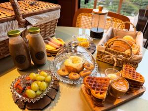 a table with a plate of food and waffles and fruit at Chalés Aframe com café da manhã artesanal, 39km de Pomerode, Hidromassagem privativa, silenciosos em meio a natureza, lagoa para pesca esportiva in Massaranduba