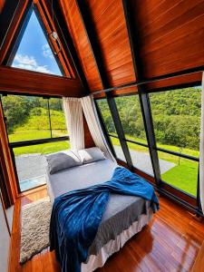 a bedroom with a bed in a room with windows at Chalés Aframe com café da manhã artesanal, 39km de Pomerode, Hidromassagem privativa, silenciosos em meio a natureza, lagoa para pesca esportiva in Massaranduba