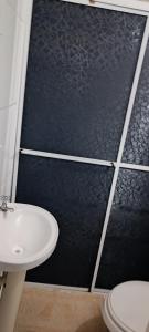 a bathroom with a black wall and a toilet and a sink at Assel Pousada Xaxim in Curitiba