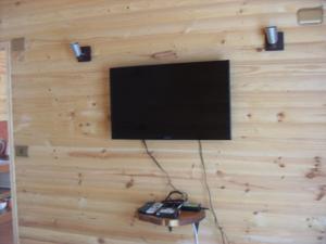 a flat screen tv hanging on a wooden wall at Eco Cabañas Algarrobo in Algarrobo