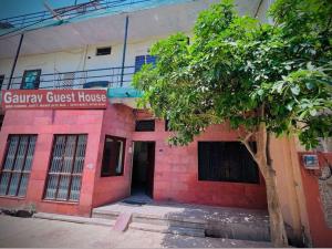 a red brick house with a tree in front of it at Gaurav Guest House in Mathura