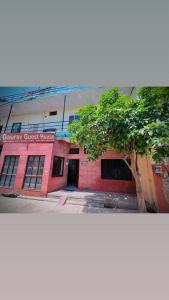 a red brick building with a tree in front of it at Gaurav Guest House in Mathura +7 photos