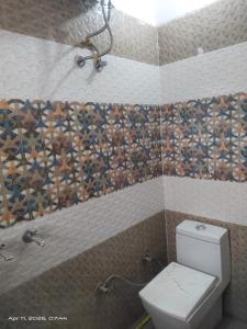 a bathroom with a toilet and a tiled wall at AC Room Double Bed 1st floor House in Mohali