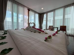 a large bed with flowers on it in a room with windows at PP Mountain Beach Resort in Phi Phi Islands +79 photos