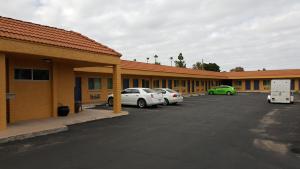 una fila de edificios con coches estacionados en un estacionamiento en Mesa Oasis Inn & Motel, en Mesa