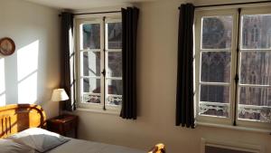 a bedroom with two windows and a bed in it at Les appartements Place de la Cathédrale in Strasbourg