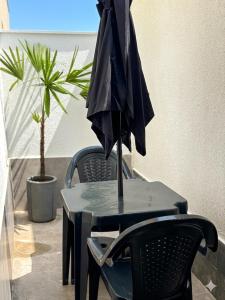a black umbrella sitting on a table with two chairs at Pousada Ocean Próx Sesc Bertioga - Beira Mar in Bertioga