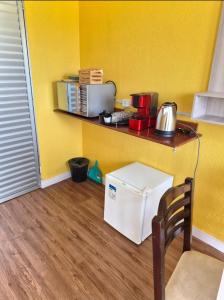 a kitchen with a yellow wall with a white refrigerator at ECO CHALÉ PARK CACHOEIRAS in Presidente Figueiredo