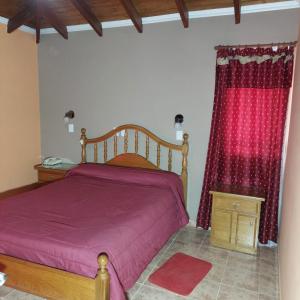 ein Schlafzimmer mit einem Bett mit lila Laken und roten Vorhängen in der Unterkunft Hotel Arauco in Aimogasta