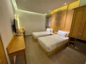 ein Hotelzimmer mit zwei Betten und einem Fernseher in der Unterkunft UNUMA HOTEL in Jakarta