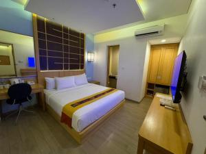 ein Schlafzimmer mit Bett, Schreibtisch und Fernseher in der Unterkunft UNUMA HOTEL in Jakarta + 12 Fotos