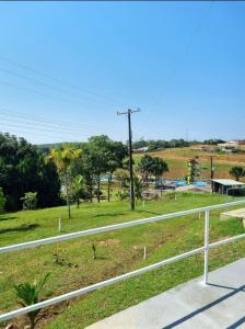 a white fence next to a field with trees at ECO CHALÉ PARK CACHOEIRAS in Presidente Figueiredo