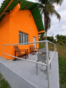 an orange house with two chairs and a table in front of it at ECO CHALÉ PARK CACHOEIRAS in Presidente Figueiredo