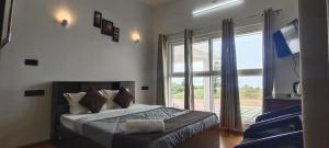 a bedroom with a bed and a large window at Adithya resort vagamon in Vagamon