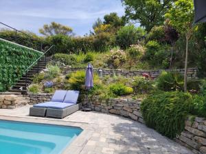 a pool with a chair and an umbrella next to a garden at TAKAMAKA in Manosque