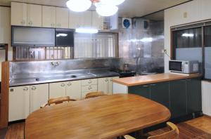 a kitchen with a wooden table and a kitchen with a microwave at ゲストハウス両浜 in Kushimoto