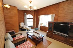 a living room with a flat screen tv and a couch at ゲストハウス両浜 in Kushimoto