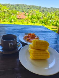 two plates of corn and a cup of coffee on a table at Tuka Cabins in Jatiluwih