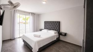 a bedroom with a white bed and a window at Apartamentos cerca al centro de Cali in Cali