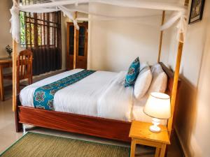 a bedroom with a canopy bed and a table with a lamp at La Planete Hotel in Rubavu