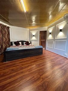 a bedroom with a large bed in a room with wooden floors at The Nigeen Lodge in Srinagar