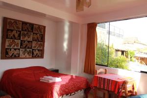a bedroom with a red bed and a window at El Mirador del Inka guest house in Cusco