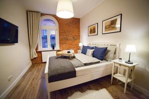 a bedroom with a bed and a brick wall at Apartamenty Pocztowa in Bydgoszcz