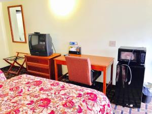 1 dormitorio con 1 cama y escritorio con TV en Greystone Motel, en Hillsboro