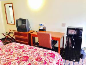 a bedroom with a bed and a desk with a tv at Greystone Motel in Hillsboro