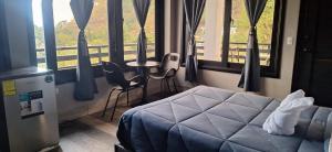 a bedroom with a bed and a table and windows at HOTEL D&S Ch'umil in Tzununá