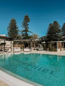 a large swimming pool with chairs and trees at Samphire Rottnest in Rottnest Island