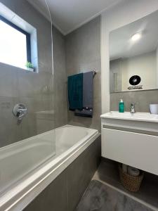 a bathroom with a bath tub and a sink at Retro Rhythm - Mossel Cove in Mossel Bay