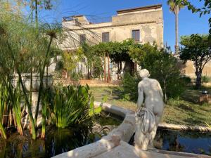 a statue in front of a pond in front of a house at Mater Familias Oasis in Syracuse