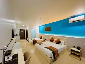 a bedroom with two beds and a blue wall at Nausori Plaza Hotel in Vunimono