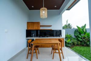 a kitchen with a wooden table and chairs at Alam Kasih Villa in Tampaksiring